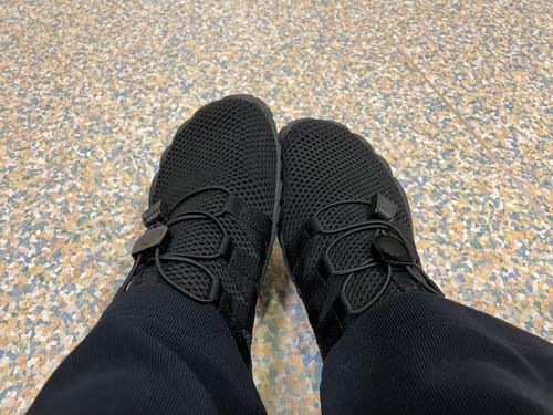 Arvostelijan jalassa mustat Vapauta Varpaat™ Paljasjalkakengät kuvaamana ylhäältä päin.