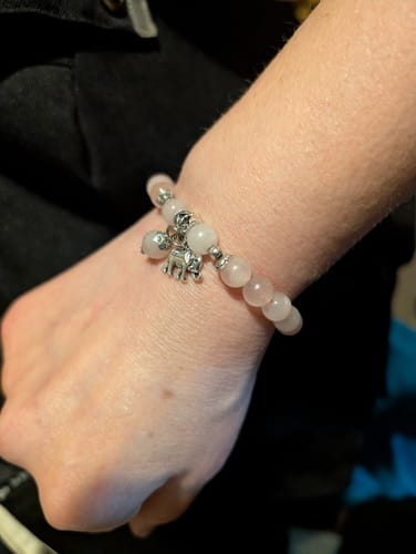 Customer's wrist, showing a beautiful crystal bracelet with light pink beads and a small elephant charm.