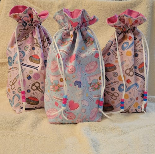 Customer's three colorful drawstring bags sewn with the Sewing Elements Fabric, featuring various sewing-themed prints.