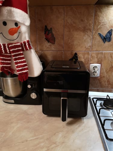 Recenzent prezintă friteuza neagră Air Fryer Novio StonePro pe blatul din bucătărie.