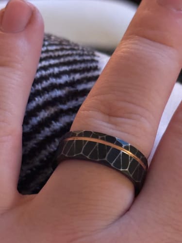 Customer's hand wearing The Stormlight ring, showing its faceted black band and contrasting rose gold inlay.