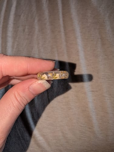 Close-up of a reviewer holding their beautiful Yellow Flower Ring with Cremains, showing the delicate flower details inside.