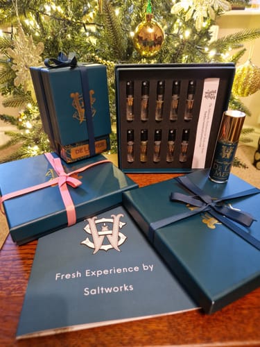 Customer's De La Mer perfume bottle and gift sets arranged on a table before a Christmas tree.