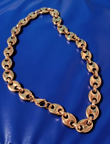 Reviewer's shiny 13mm Polished Gold Puffed Mariner Link Chain on a blue surface.