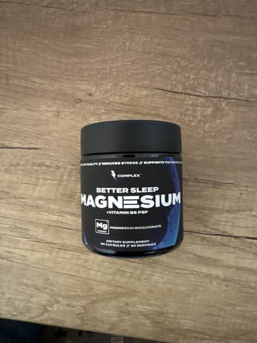 Customer's black jar of Complex Sleep Magnesium resting on a wooden table.