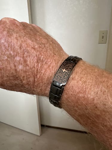 Customer wearing their black link-style FIDES Cross Bracelet on their wrist, showing the engraved center plate.