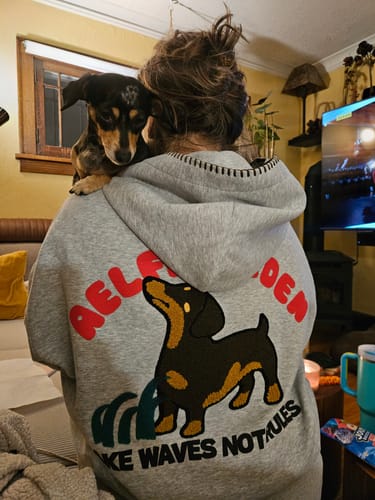 Reviewer from behind in an oversized grey Dachshund Pullover Hoodie with a matching dachshund on their shoulder.