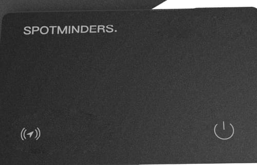 Close-up of a customer's black SPOTMINDERS tracking card showing the brand name and icons.