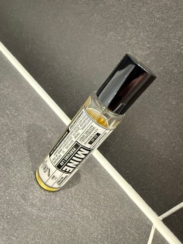 Cliente mostra il flacone di profumo VESEVO su uno sfondo piastrellato grigio.