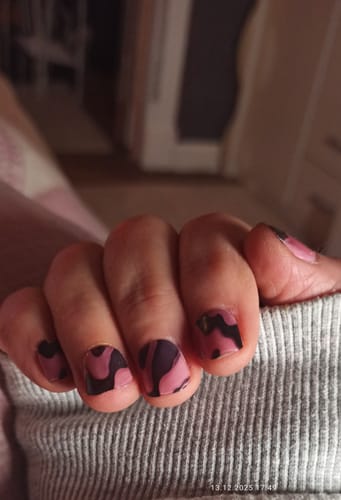 Nahaufnahme der Hand einer Rezensentin, die die schwarz-pinken Silk Drip UV-Gel-Nagelfolien trägt.
