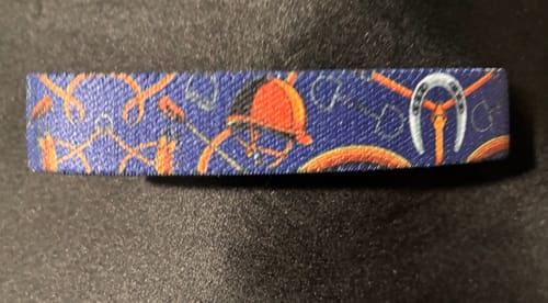Customer's blue fabric ZOX bracelet with an orange pattern of riding helmets, reins, and horseshoes.