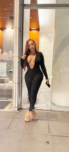 Customer walking outdoors in the slim-fit black Rio Bodysuit with a deep plunge neckline.