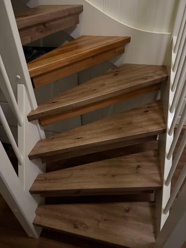 Anmelder viser fremdriften med å legge Artisan Oak kontaktplast på trinnene i en hvit vindeltrapp.