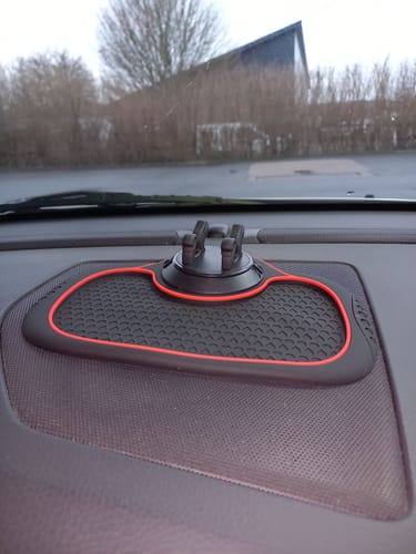 Anmelders skridsikre telefonholder med måtte vist på et instrumentbræt i en bil.