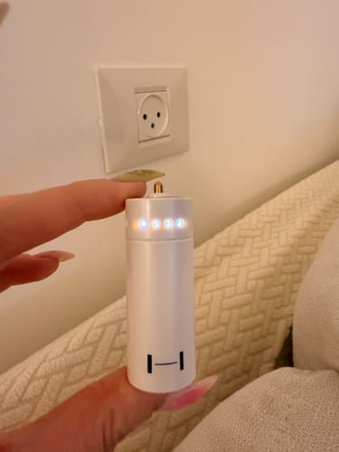 Reviewer holding the white HYBE Official Light Stick Battery with its top LED indicator lights glowing.