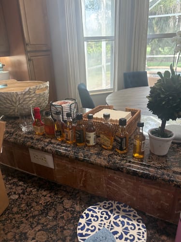 Reviewer's Bourbon Whiskey Tasting Bundle Kit with ten mini bottles arranged on a kitchen counter.