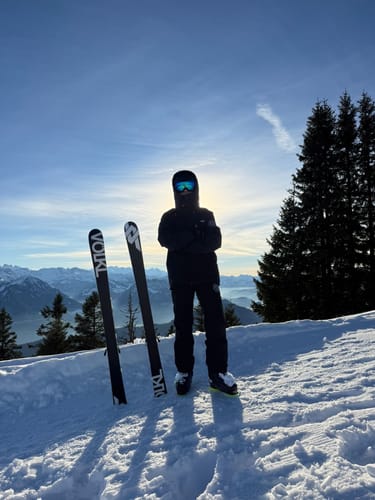 Reviewer standing on a snowy mountain wearing the black baggy snow pants.