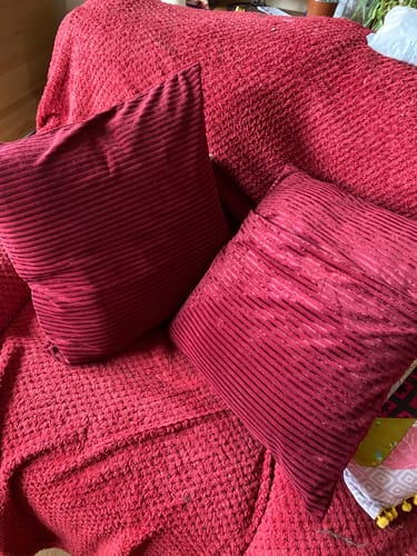 Customer's two pillows made from red Lineage Luxe Velvet Velour Fabric resting on a sofa.