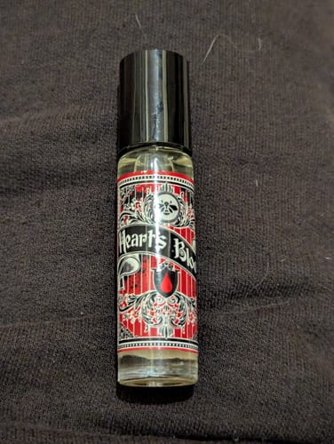 Customer's roll-on bottle of Heart's Blood perfume, showing the ornate red and black label.