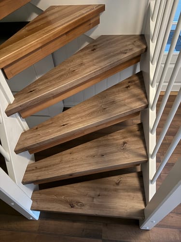 Anmelder viser det ferdige resultatet med Artisan Oak kontaktplast på alle trinnene i en hvit trapp.