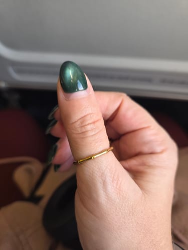 Close-up of a customer's thumb wearing the gold Bamboo Stacker Ring.