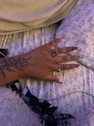 Customer's tattooed hand wearing the detailed Centipede Ring on the ring finger.