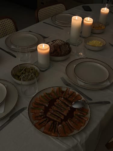 Beoordelaar toont het by fonQ Loods serviesset op een sfeervol gedekte tafel met brandende kaarsen.