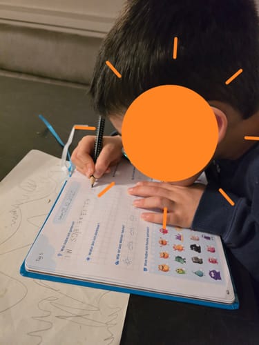 Ein Kind schreibt konzentriert in das geöffnete Edubini Gefühlstagebuch.