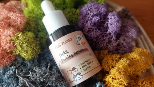 Серумът Doori Egg Planet на рецензент, аранжиран сред цветен мъх.