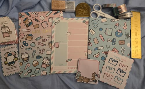 Reviewer's collection of cute stationery items from the Holiday Happy Mail Advent Calendar laid out on a blue background.