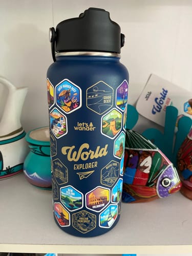 Customer's dark blue World Explorer Bottle customized with many colorful travel stickers.
