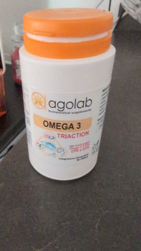 Un cliente mostra il flacone di Omega 3 Tri-Action, bianco con un tappo arancione, appoggiato su un bancone.