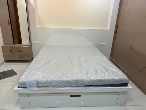 Customer's new Flo Anti-Gravity™ Latex Mattress in plastic wrapping on a white bed frame in a bedroom.