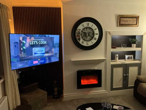 Reviewer's dark Premium Acoustic Slatted Wall Panels installed as a feature wall behind a television in a living room.