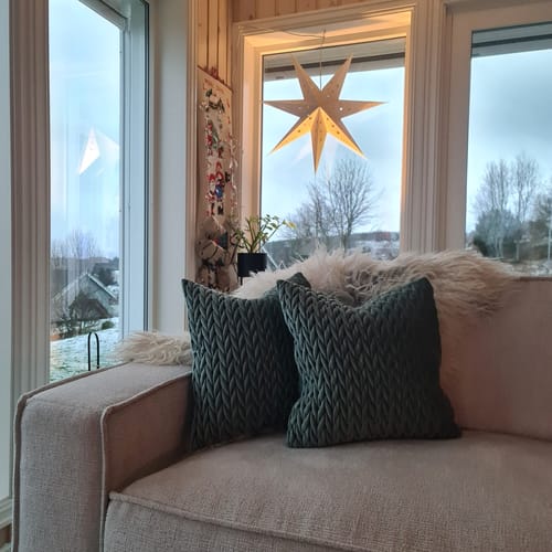 Kundens to grønne, flettede velurputetrekk plassert i en lys sofa.