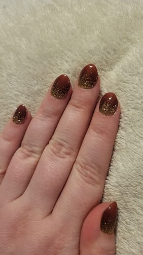 Kundenrezension: Eine Hand zeigt die 'Red Velvet Gold' UV-Gelnägel mit einem dezenten roten und goldenen Glitzer-Ombré-Design.