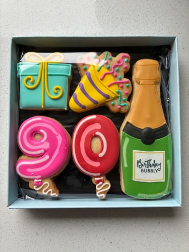 Customer's Birthday Balloon Biscuit Box with colorful iced biscuits for a 90th birthday, including a champagne bottle.