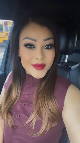 Customer's close-up selfie in a car wearing the sleeveless, burgundy Marlo Knit Pleated Set top.