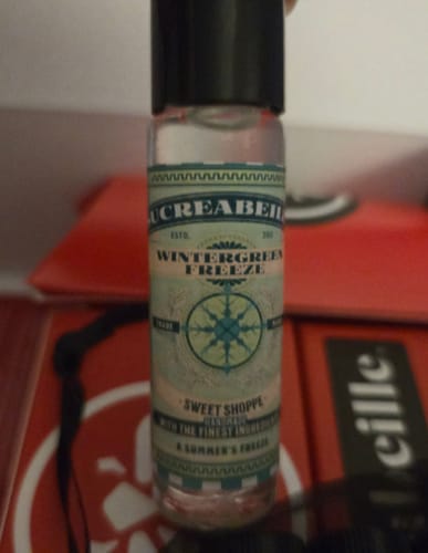 Customer holding a small rollerball bottle of Wintergreen Freeze, showing the detailed product label.