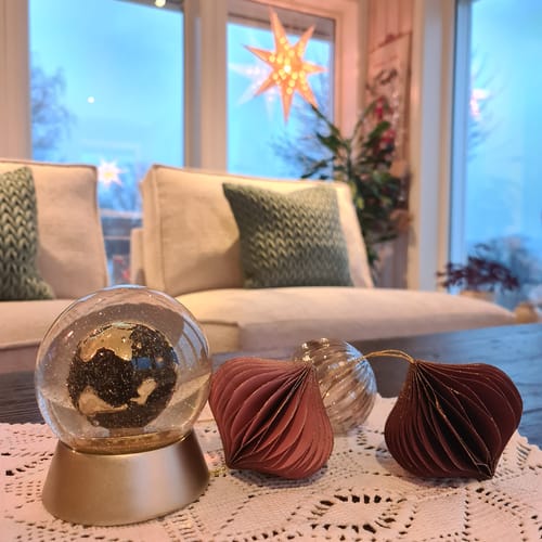 Kundes nærbilde av de løkformede julekulene i papir på et bord med annen julepynt.