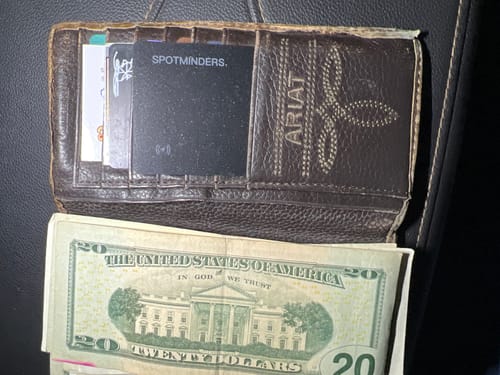 Customer's black SPOTMINDERS Tracking Card tucked inside a brown leather wallet.