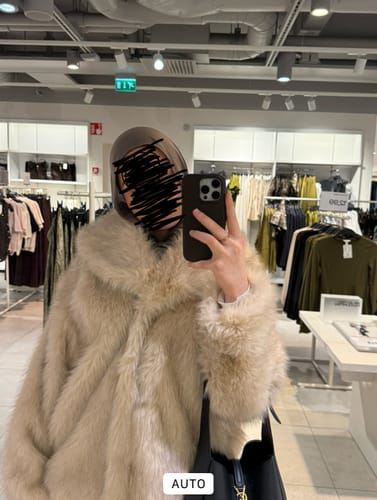 A reviewer takes a mirror selfie in a clothing store wearing the soft Kahve Premium Modal hijab.