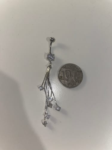 Reviewer's Night Deity Belly Dangle laid flat on a white surface next to a coin for scale, showing the long chains.