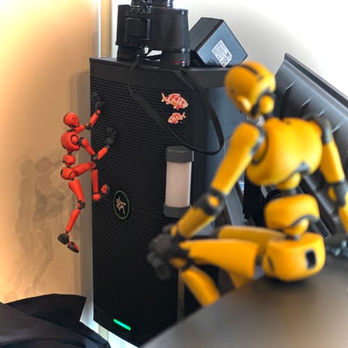 Customer's two Stickybones figures posed for an adventure, with the red Black Lava figure climbing a speaker.