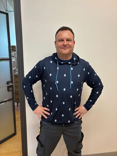 Customer posing in the dark blue Star Wars '12 Parsecs' Performance Hoodie with its all-over Millennium Falcon pattern.