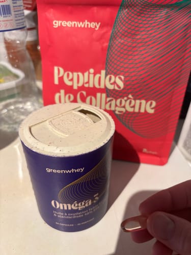 Un client tenant une gélule d'Oméga 3 à côté du pot violet du produit.