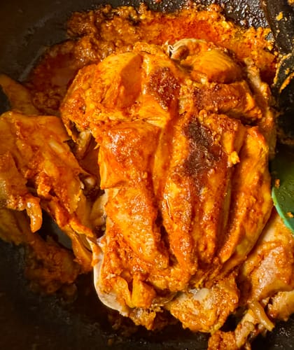 Reviewer's Halal Whole Chicken cooking in a pan, covered in a thick, reddish sauce.