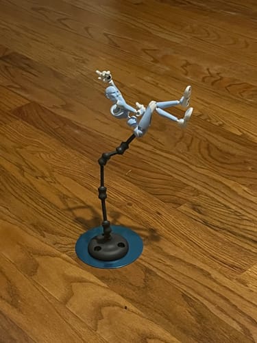 Customer's Glacier Blue Stickybones figure holding a dynamic pose while attached to the Fly-Rig stand on a wood floor.