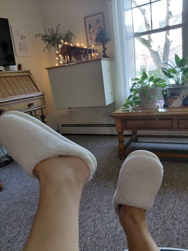 Customer's first-person view of their feet in white plush Nordic Plush Slippers while relaxing.
