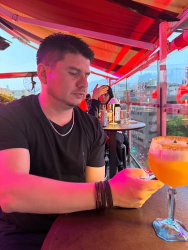 Un cliente sentado en un bar, luciendo su Cadena Miami Cuban plateada de 5mm con una camiseta negra.